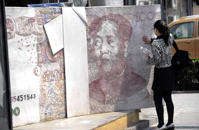 Gefhlte Inflation: Eine Frau berhrt eine Skulptur in Peking.   | Foto: AFP