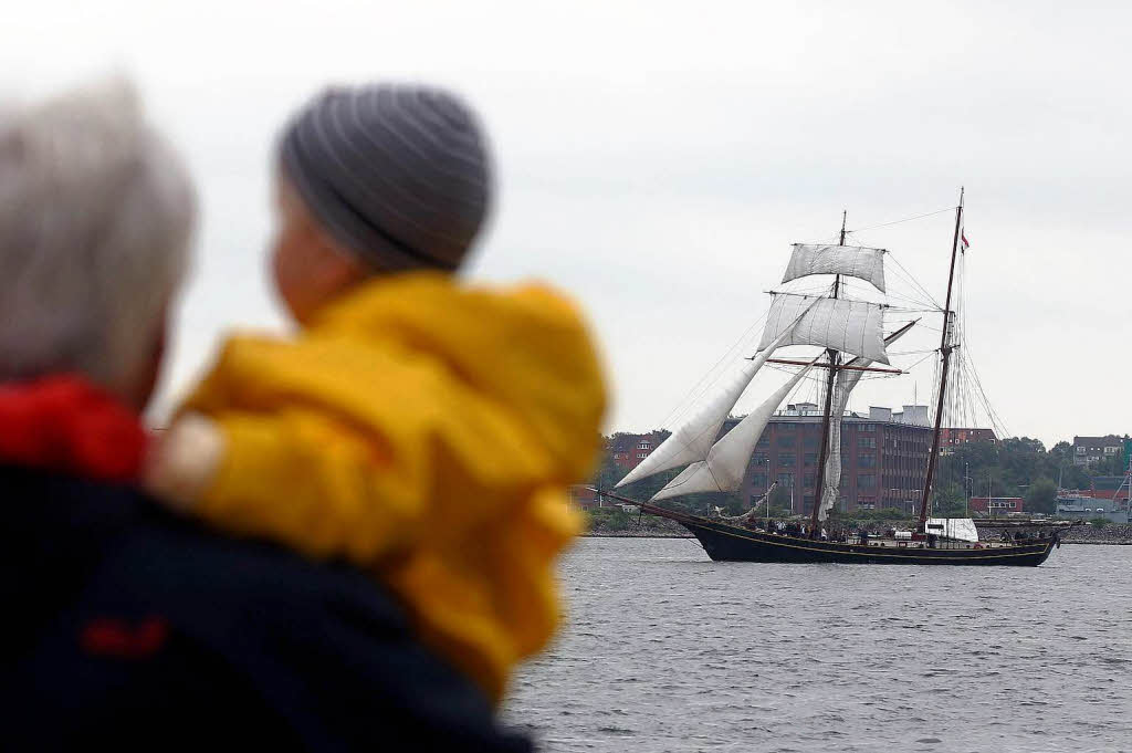 Ein Mann mit Kind schaut in Kiel auf ein Segelschiff whrend der Kieler Woche.