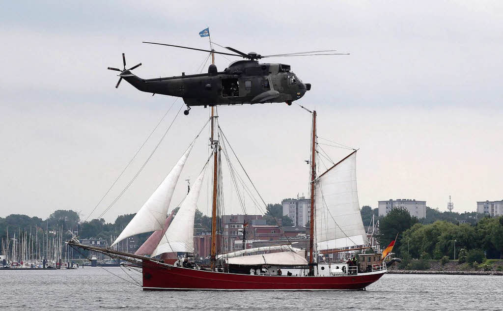 Ein Hubschrauber der Bundeswehr fliegt im Rahmen der Kieler Woche ber einem Segelschiff.