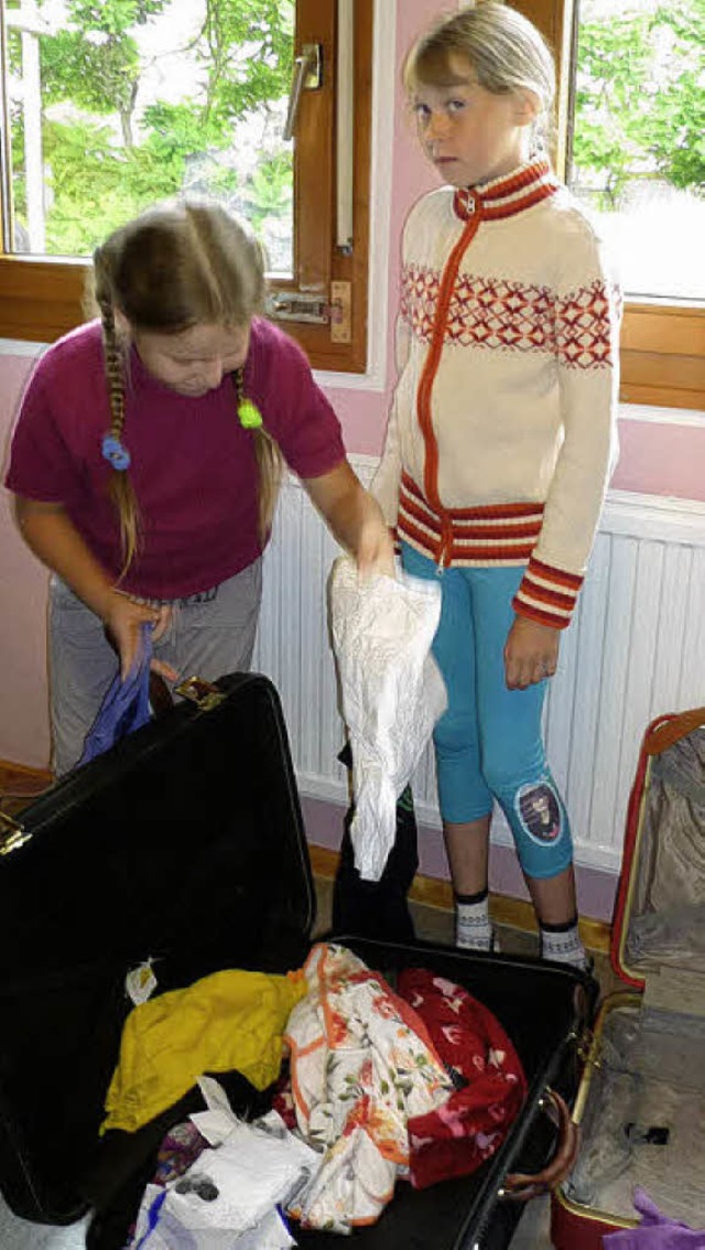Ein Mdchen legt ihre ausgesuchten Kleider in einen der gespendeten Koffer.   | Foto: Gabriele rasenberger