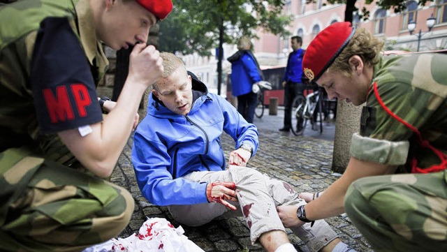 Die Militrpolizei kmmert sich in Oslos Stadtzentrum um einen verletzten Mann.   | Foto: DPA