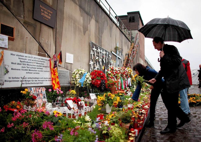 Menschen legen am Sonntag in Duisburg ...m Jahr passierte dort die Katastrophe.  | Foto: dpa