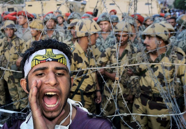 Ein Demonstrant in Kairo vor Maschendraht und Soldaten   | Foto: afp