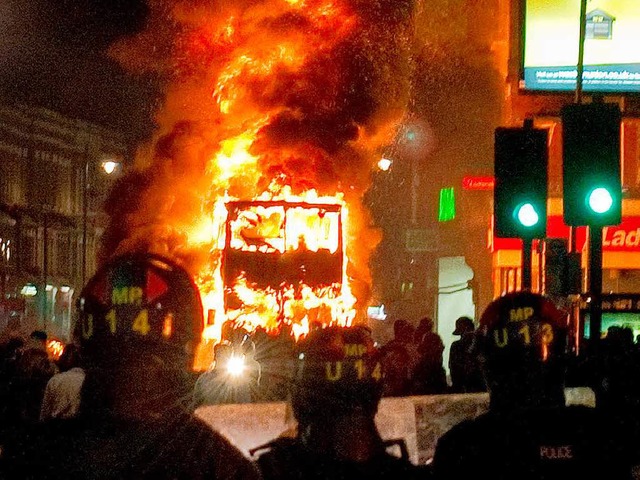 Polizisten vor einem  brennenden Doppeldeckerbus   | Foto: AFP