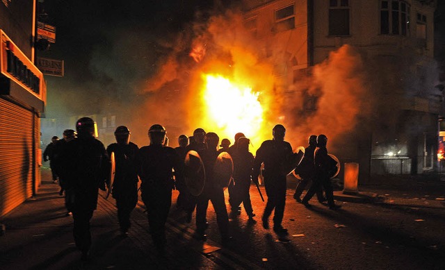 Polizisten treffen in der Nacht auf Dienstag vor einem brennenden Gebude ein.   | Foto: AFP