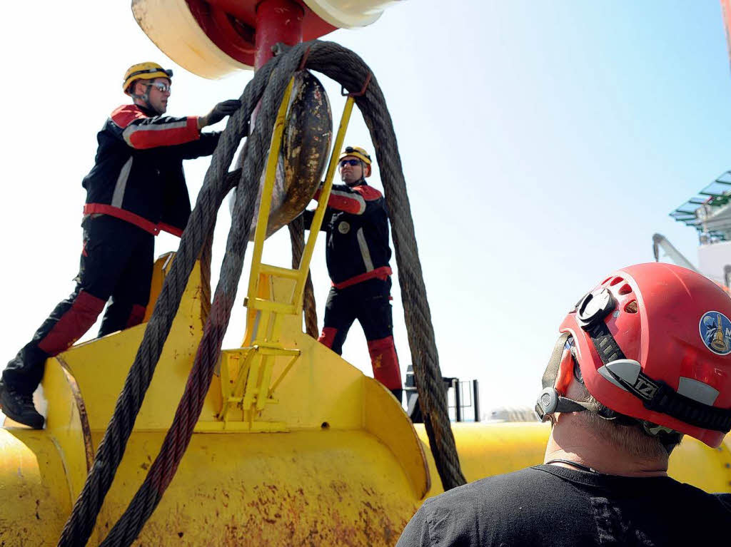 Arbeiter bereiten auf dem Errichterschiff "Wind Lift 1" eine Traverse zum Entladen neuer Bauteile fr das Sttzkreuz-Fundament vor.