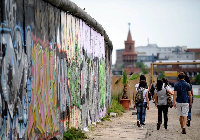 In Berlin sehen sich viele Touristen die Reste der Mauer   an.  | Foto: dpa