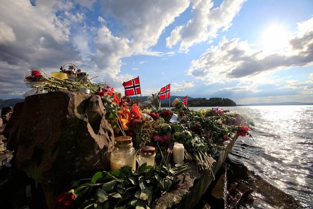 Blumen und  Fahnen erinnern an die Opf... auf der Insel   Utya im Hintergrund.  | Foto: dapd