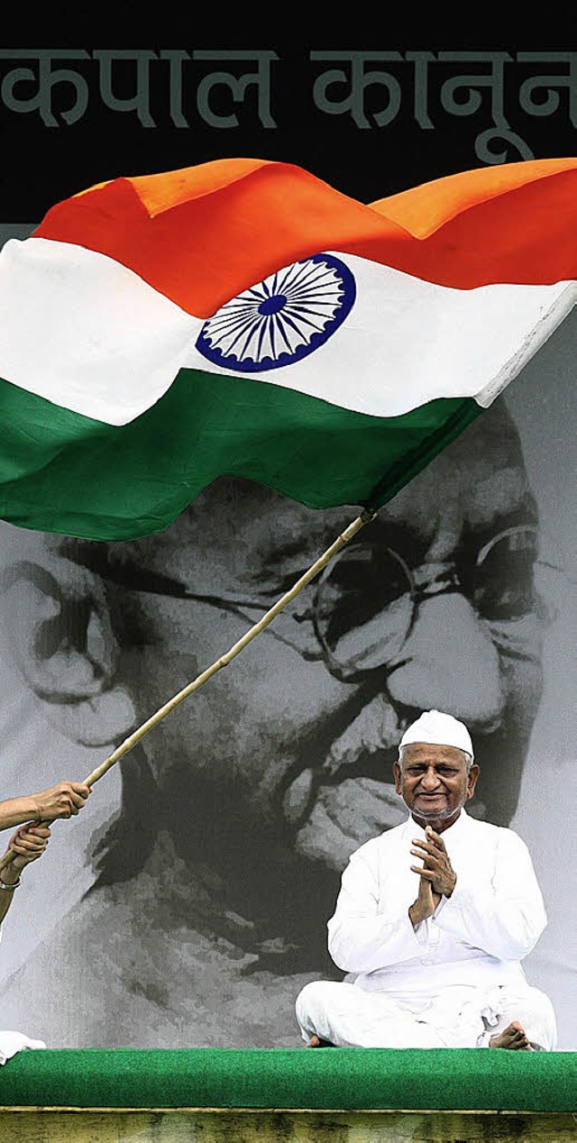 Anna Hazare sitzt vor einem Bild des Freiheitskmpfers Mahatma Ghandi.   | Foto: DPA
