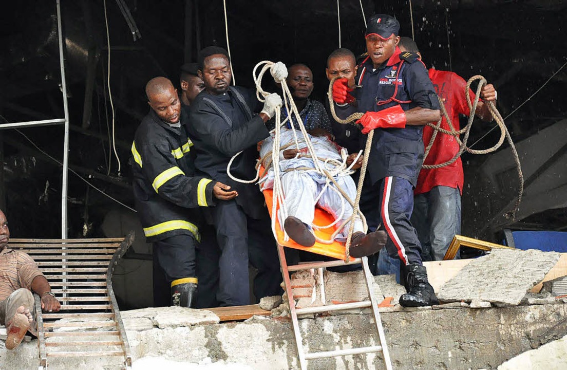 Hilfskräfte retten einen Verletzten aus dem zerbombten Gebäude in Abuja.   | Foto: AFP