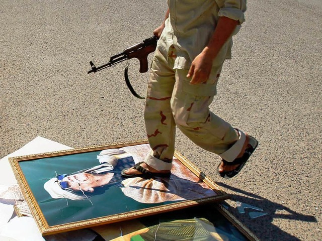 Ein bewaffneter Aufstndischer tritt i...hrigen Machthabers Muammar al Gaddafi.  | Foto: dapd