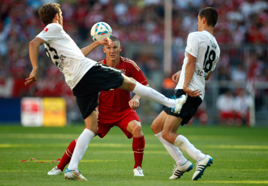 Johannes Flum und Julian Schuster vom SC Freiburg sowie Bastian Schweinsteiger (FC Bayern Mnchen).