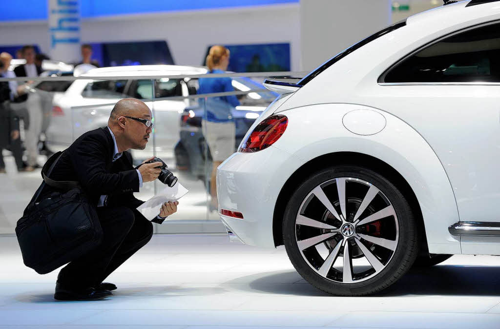 Ein Messebesucher nimmt  den neuen VW Beetle unter die Lupe.