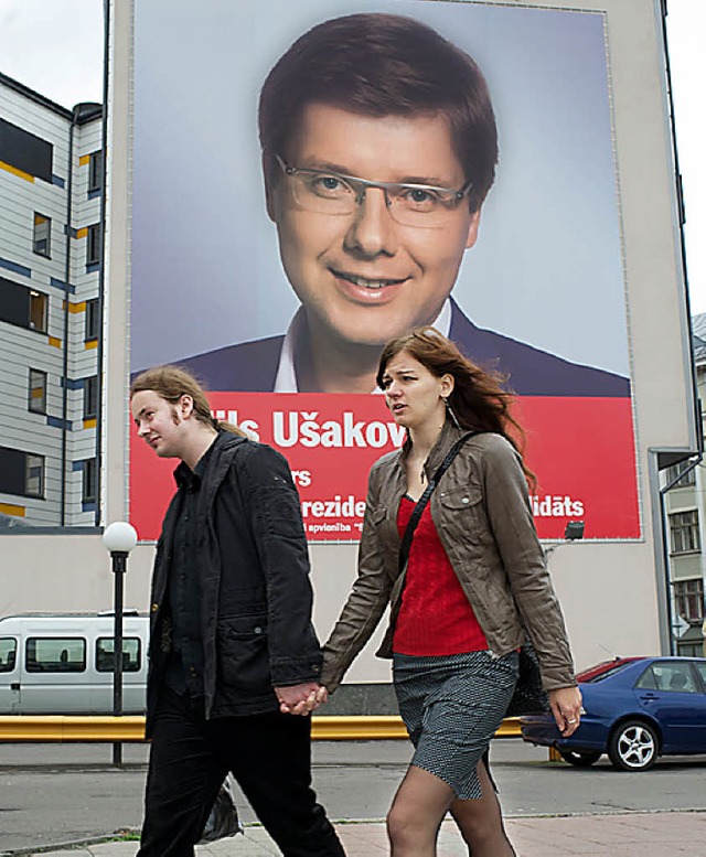 Ein Paar auf dem Weg zur Wahl, dahinte... Partei Harmoniezentrum, Nils Usakovs   | Foto: afp