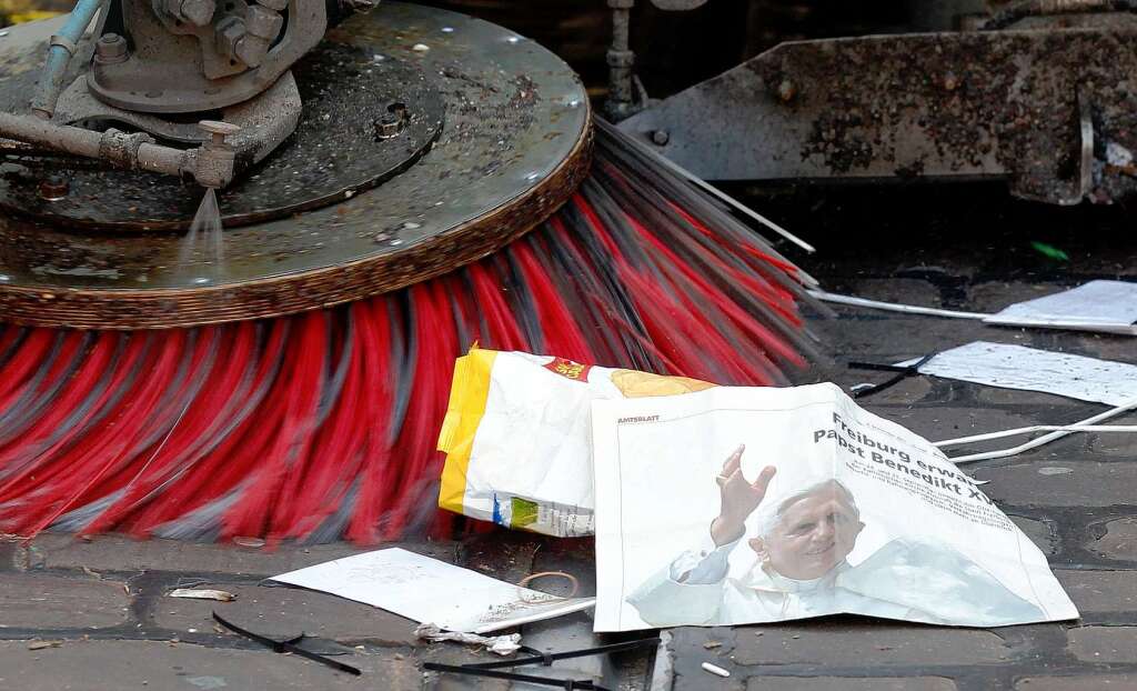 Eine Kehrmaschine beseitigt eine Zeitung mit dem Konterfei des Papsts.