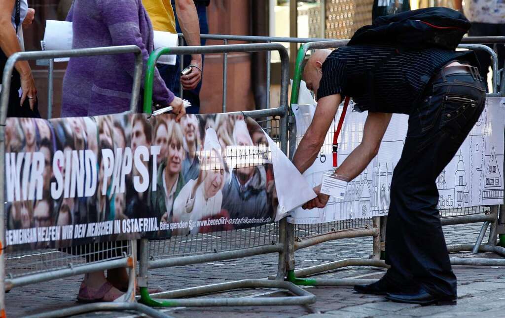 Ein Mann entfernt nach der Durchfahrt von Papst Benedikt XVI. ein Plakat, auf dem "Wir sind Papst" steht, von einem Absperrgitter.