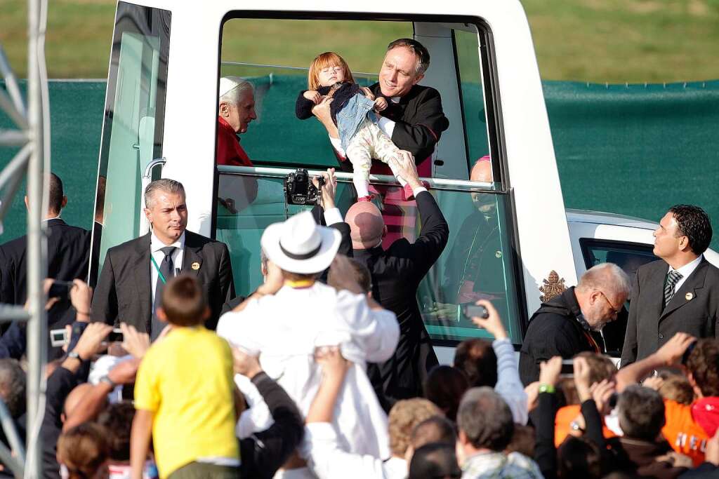 Der Papst segnt ein Kleinkind im Papamobil.