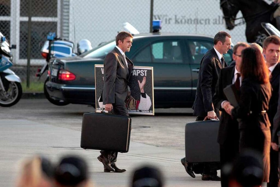 Ein Mitarbeiter des Papstes trägt am Sonntag auf dem Flughafen in Lahr einen Koffer und eine Grafik aus mahr als 10.000 Einzelbildern, die die Schlagzeile der BILD-Zeitung "Wir sind Papst" aus dem Jahr 2005 darstellt. Das Bild wurde Papst Benedikt XVI. von einem Vertreter der Deutschen Telekom als Geschenk überreicht. (Foto: Christoph Breithaupt) Ein Mitarbeiter des Papstes trägt am Sonntag auf dem Flughafen in Lahr einen Koffer und eine Grafik aus mahr als 10.000 Einzelbildern, die die Schlagzeile der BILD-Zeitung "Wir sind Papst" aus dem Jahr 2005 darstellt. Das Bild wurde Papst Benedikt XVI. von einem Vertreter der Deutschen Telekom als Geschenk überreicht. (Foto: Christoph Breithaupt)
