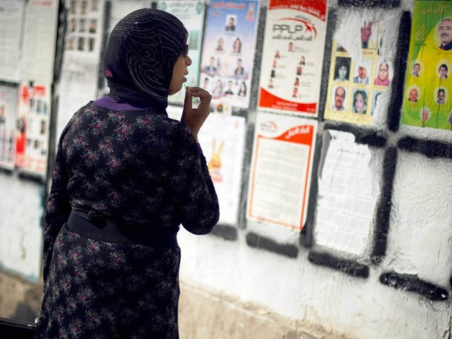 Wen whlen? Eine Frau studiert die Pla...on Kandidaten auf einer Wand in Tunis.  | Foto: AFP