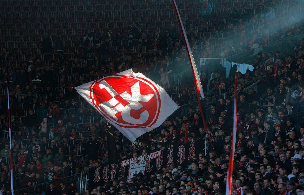 Fans von Kaiserslautern schwenken eine Fahne mit dem Logo des Vereins in ihrem Fanblock.