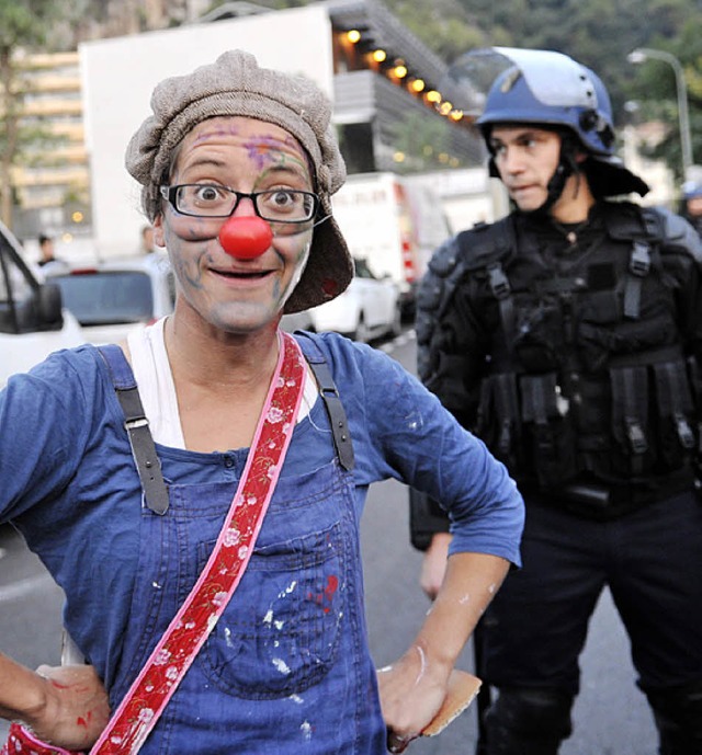 Eine Frau demonstriert in einer Clownsmaske.   | Foto: AFP