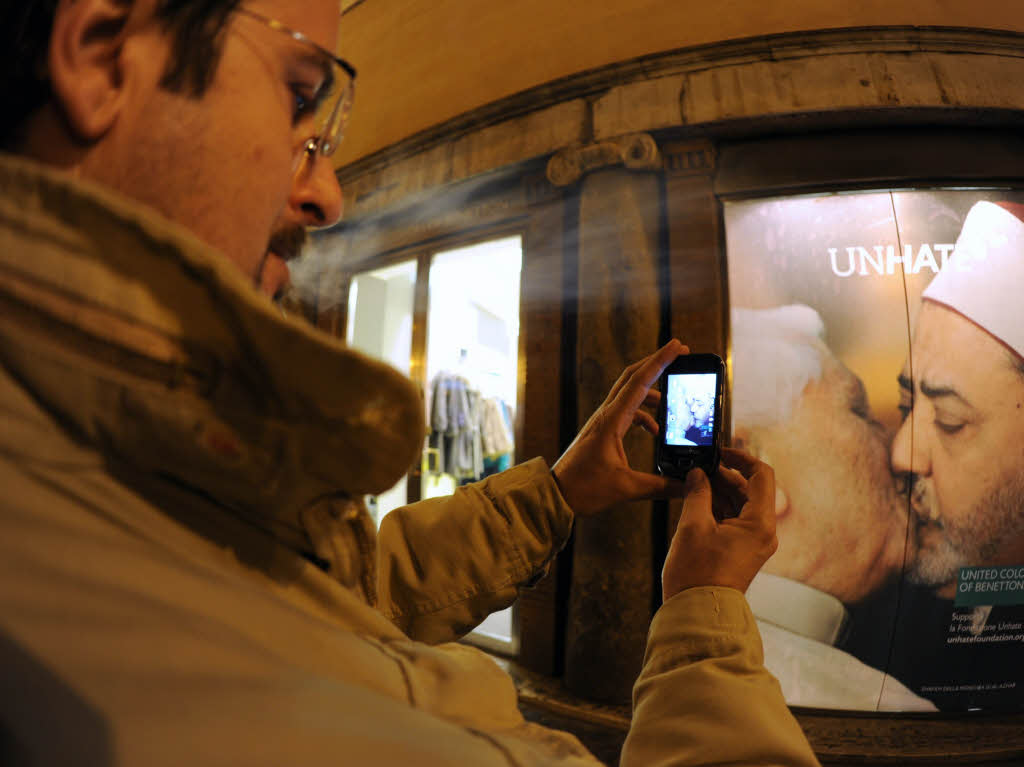 Ein Italiener macht ein Handyfoto vom kssenden Papst.