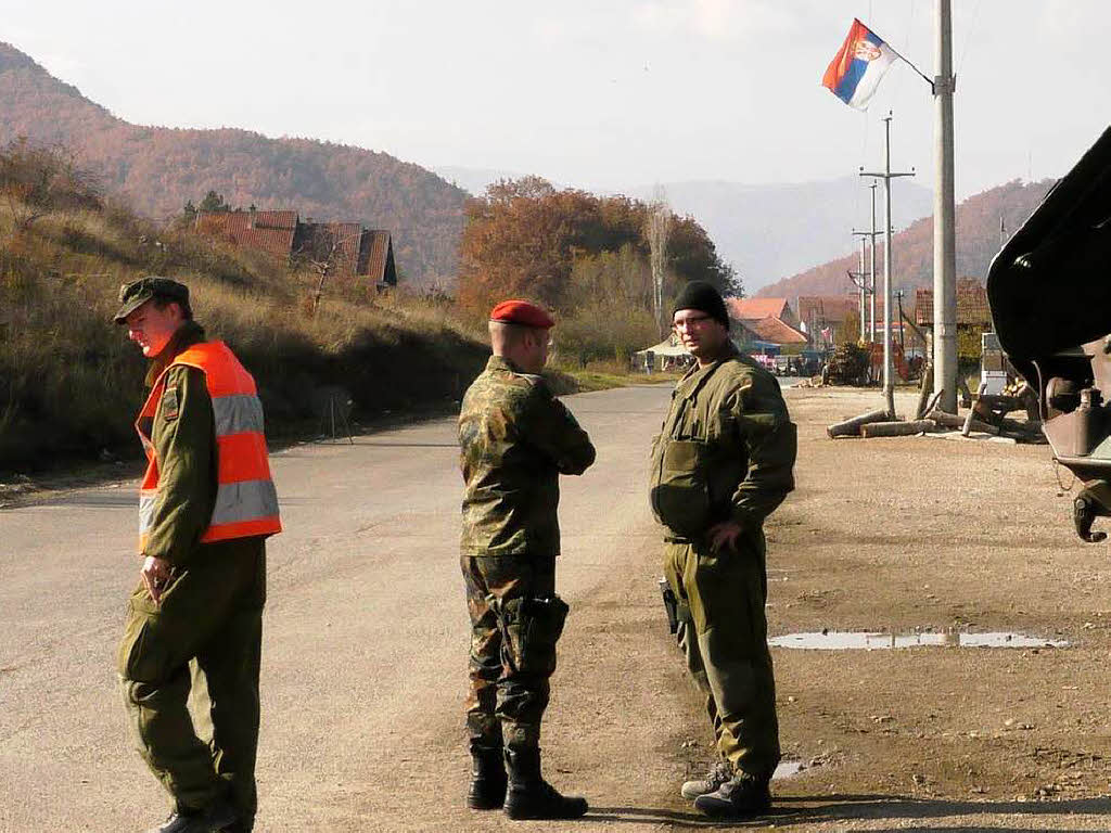 Bundeswehrsoldaten beob-achten einen der beiden Road-Blocks . An  Straenlaternen und Strommasten hngt die serbische Flagge.
