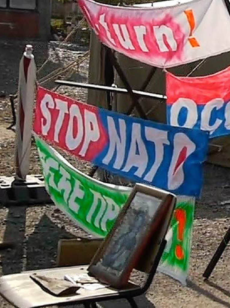 „Stoppt die Nato“, „Stoppt die Besatzung“, ist auf den Plakaten  zu lesen. Auf einem Stuhl haben die Menschen eine Jesus-Ikone platziert.