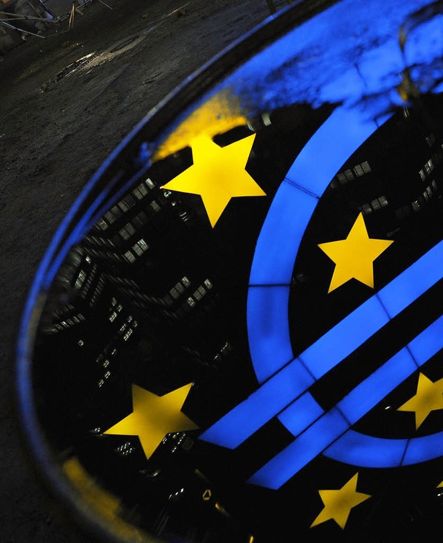 In einer Regenpftze vor der Europisc...kfurt   spiegelt sich das Euro-Symbol.  | Foto: dpa