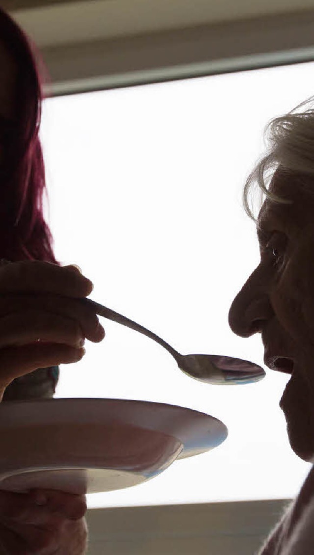 Einer Seniorin wird in einem Alten- und Pflegeheim beim Mittagessen geholfen.   | Foto: DPA
