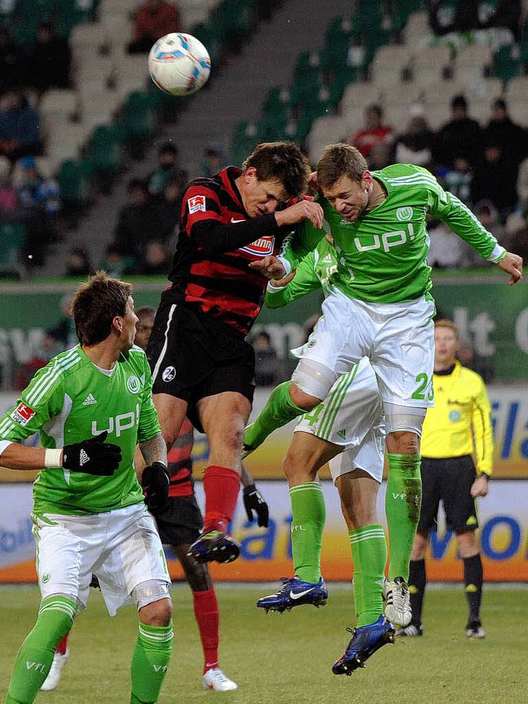Der Wolfsburger Marco Russ (r) und der Freiburger Spieler Ivan Santini (M) im Kopfballduell.