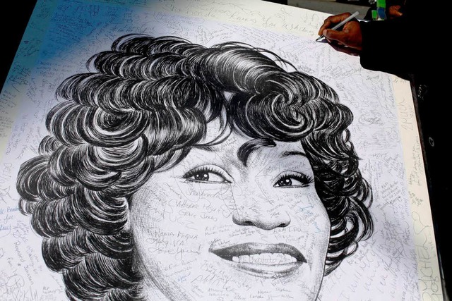 Bei der Trauerfeier fr Whitney Houston signieren Fans ein Bild von ihr.  | Foto: AFP