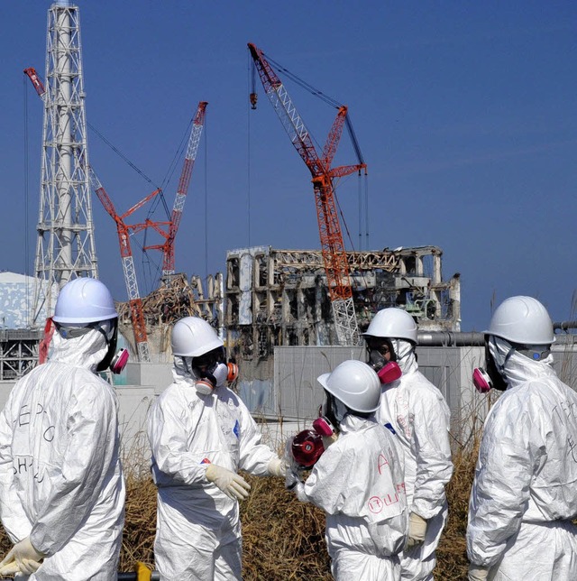 Tepco-Arbeiter vor den Resten der Reaktoren in Fukushima   | Foto: AFP