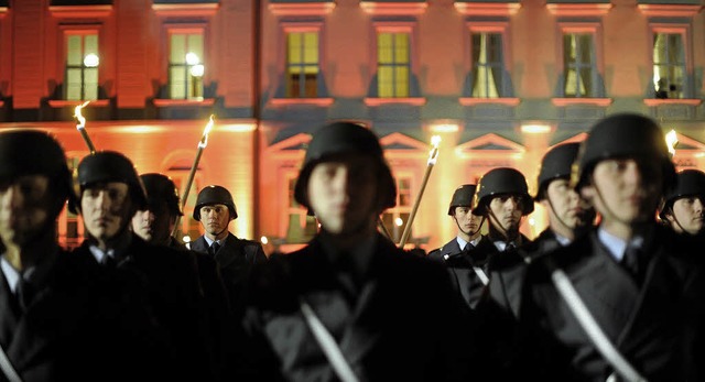Soldaten beim Groen Zapfenstreich vor dem beleuchteten Schloss Bellevue  | Foto: afp