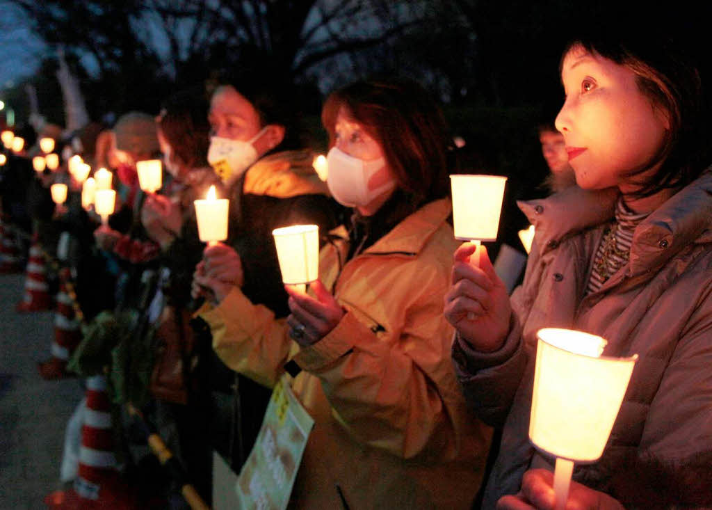 Kinder gedenken mit einer Lichterkette der Umweltkatastrophe in Japan.