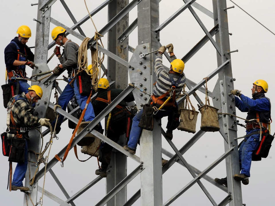Arbeiter montieren einen neuen Stromma...ere Tausend Kilometer neue Leitungen.   | Foto: dapd