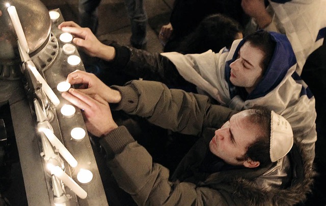 Bei einem Schweigemarsch in Paris gedenken zwei Mnner der Opfer mit Kerzen.   | Foto: AFP