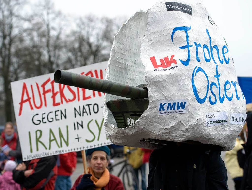 Ein Demonstrant trgt am Samstag in Mnchen whrend eines Ostermarsches ein stilisiertes Osterei mit der Aufschrift "Frohe Ostern", aus dem ein Panzer gefahren kommt, auf dem Kopf.