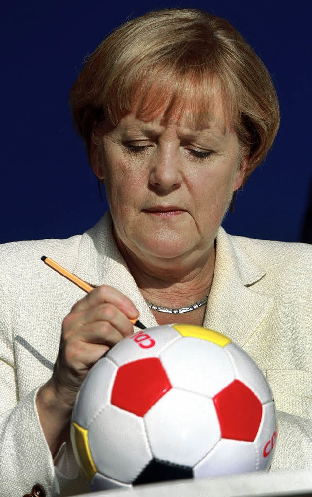 Mit diesem Ball wird bei der EM in der...a Merkel beim Signieren eines Fuballs  | Foto: dpa