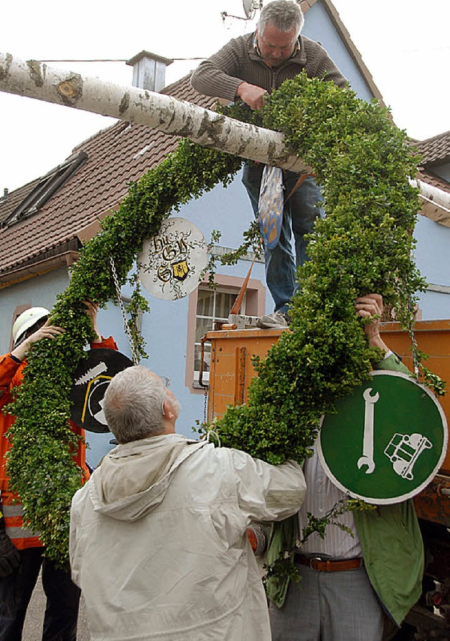 Mitglieder der Feuerwehr und des Heima...festigen den Maikranz am Birkenstamm.   | Foto: Roland Vitt