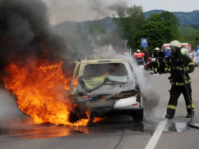 Ein Feuerwehrmann lscht am Samstag au...B294 bei Freiburg ein brennendes Auto.  | Foto: dpa