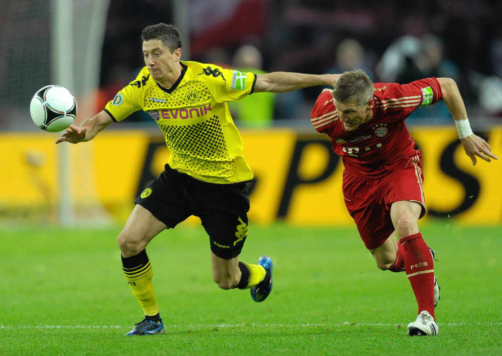 Mnchens Bastian Schweinsteiger und der Dortmunder Robert Lewandowski kmpfen um den Ball.