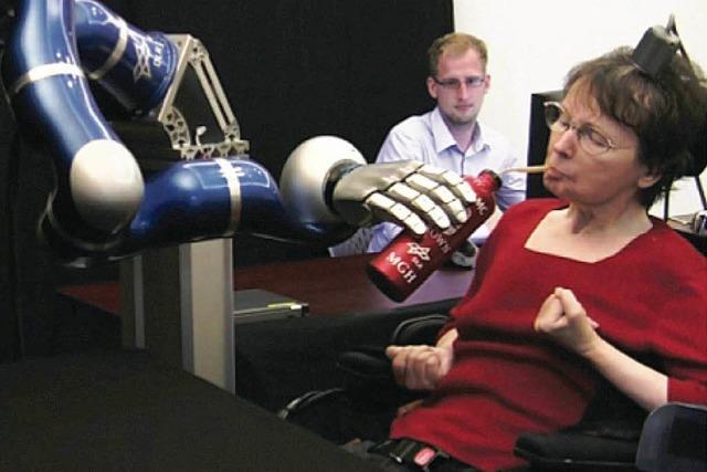 Gelähmte Frau dirigiert Roboterarm mit ihren Gedanken