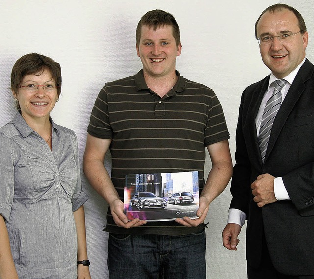 Andreas Kreuz (Mitte)  mit einem Foto ...stadt, und Vorstand Stephan Heinisch.   | Foto: Volksbank Freiburg