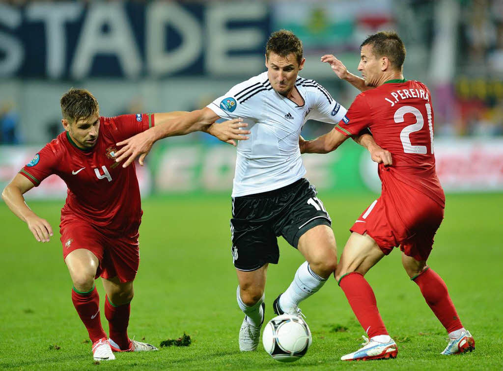 Miroslav Klose setzt sich gegen Portugals Joao Pereira durch.