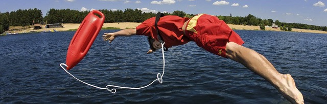 Ein  DLRG-Rettungsschwimmer springt whrend einer bung in das Wasser  | Foto: DPA