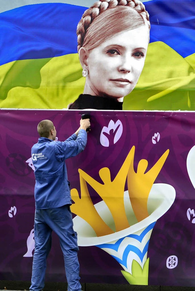 Ein Arbeiter berklebt auf der Fanmeil...lakat mit dem Konterfei Timoschenkos.   | Foto: DAPD