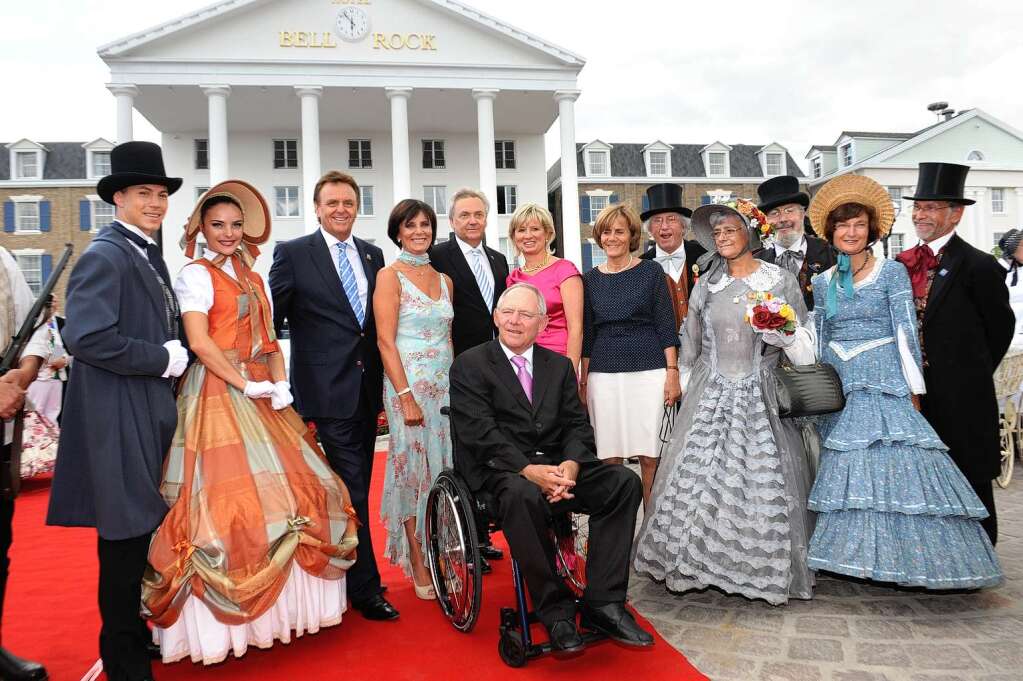 Bundesfinanzminister Wolfgang Schuble posiert  mit der Familie Mack und kostmierten Damen und Herren vor dem neuen Hotel.