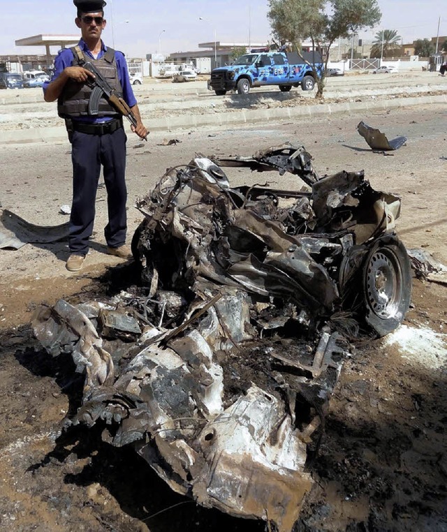 Ein Auto nach einem Autobombenanschlag...lizist steht in Kirkuk vor dem Wrack.   | Foto: dpa