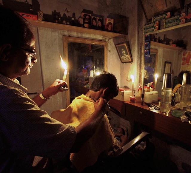 Ein Frisr in Kalkutta schneidet einem...waren  620 Millionen Inder ohne Strom.  | Foto: dapd